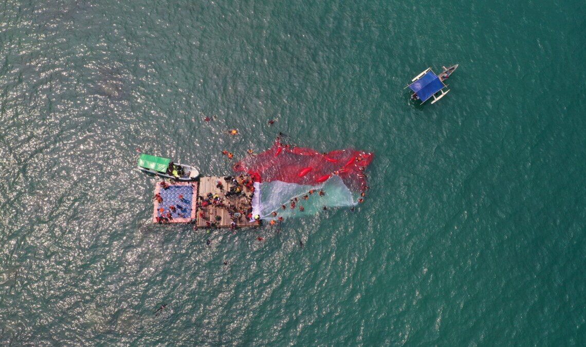 Simbol Cinta Tanah Air, Ratusan Relawan Bentangkan Merah Putih Raksasa di Perairan Merak